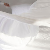 Person making the bed with luxury bed sheets